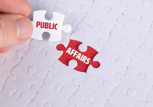 Hand holding piece of jigsaw puzzle with word public & affairs
