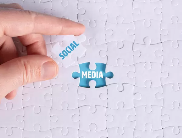 Hand holding piece of jigsaw puzzle with word social & media