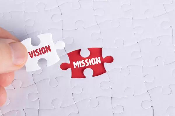Hand holding piece of jigsaw puzzle with word vision & mission