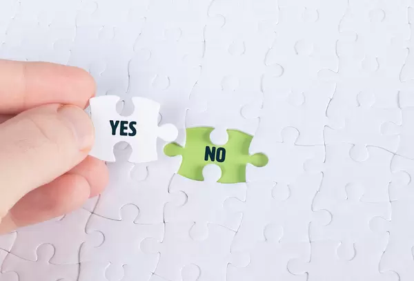 Hand holding piece of jigsaw puzzle with word yes & no