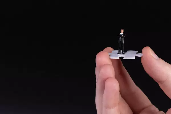 Hand holding puzzle piece with businessman