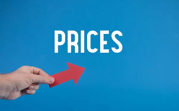 Hand holding red arrow and Prices text on blue background