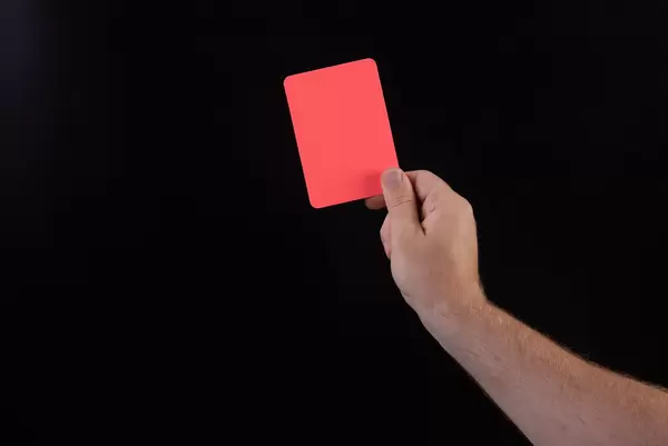 Hand holding red referee card with on black background
