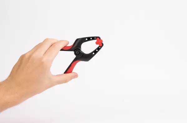 Hand holding small clamp on white background