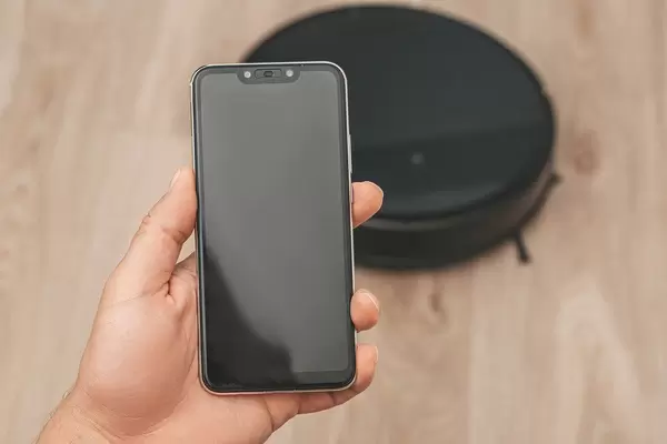 Hand holding smartphone to control the robot vacuum cleaner