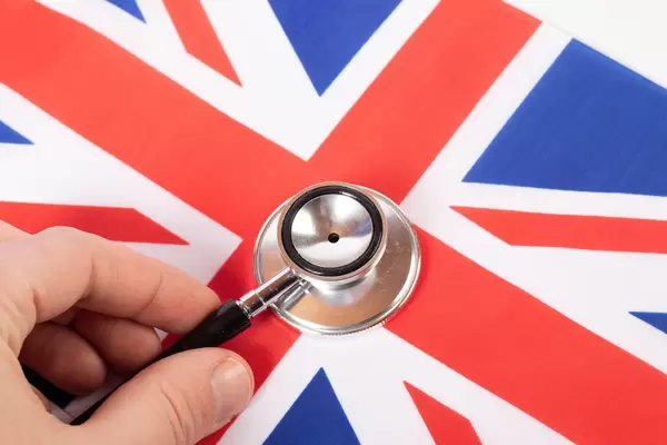 Hand holding stethoscope on British flag