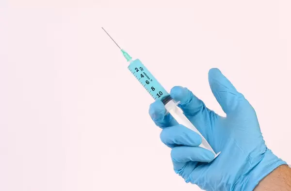 Hand holding syringe with blue fluid