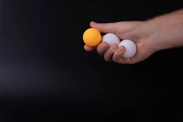 Hand holding table tennis balls on black background
