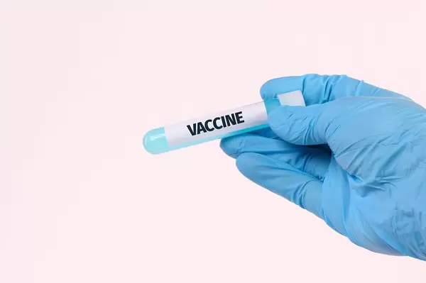 Hand holding test tube with text VACCINE on white background