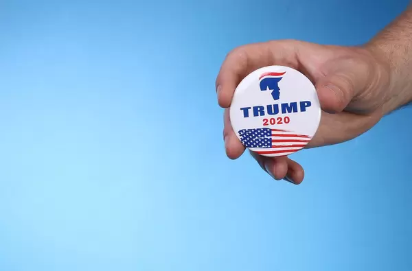 Hand holding Trump 2020 badge