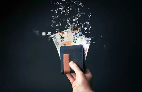 Hand holding wallet with euro money tearing apart