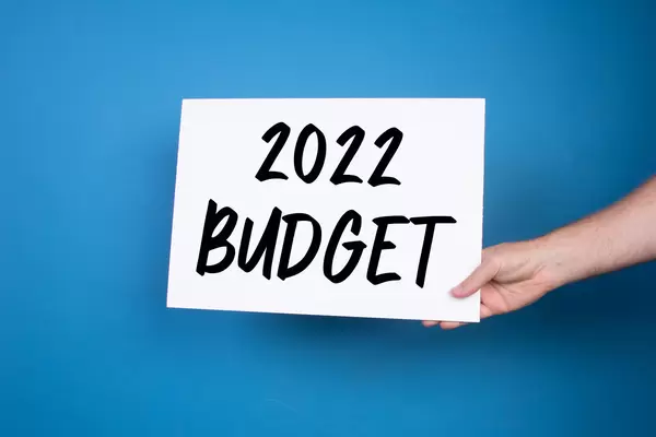 Hand holding white banner with 2022 Budget text on blue background