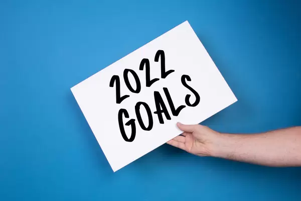 Hand holding white banner with 2022 Goals text on blue background
