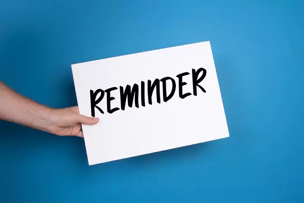 Hand holding white banner with Reminder text on blue background