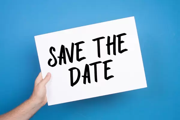 Hand holding white banner with Save the Date text on blue background