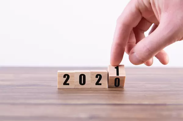 Hand holding wooden cube with flip over block 2020 to 2021