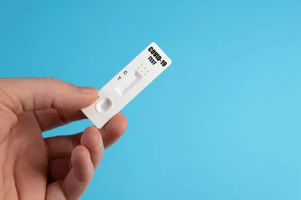 Hand holds a covid-19 antigen test on blue background
