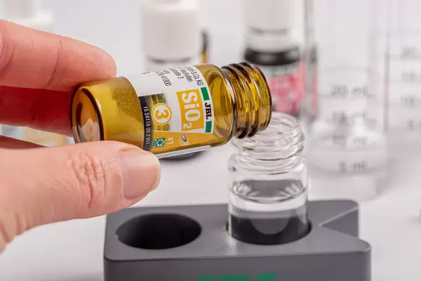 Hand holds a reagent sio2 or silicium for testing water, close-up