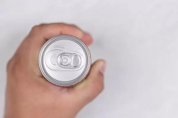 Hand holds closed can top view with blurred background