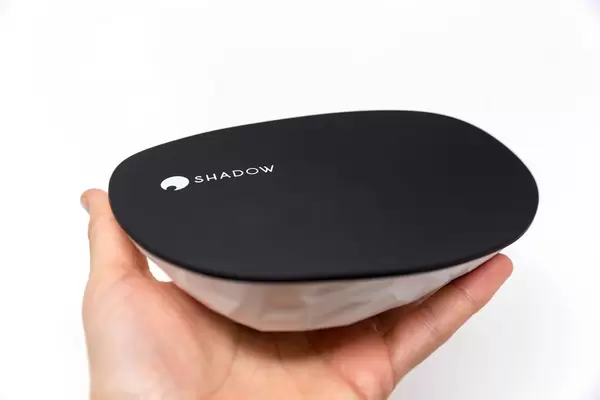 Hand holds Shadow Ghost with curved design in black and white for Cloud Gaming in front of white background