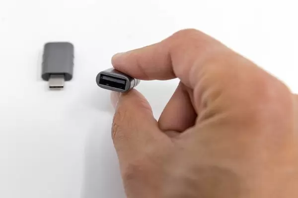Hand holds small Syntech adapter and shows input and output for USB C and USC OTG ports
