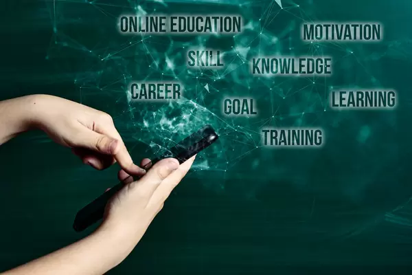 Hand holds smartphone near chalkboard with text clouds - online education, motivation, skill, career, goal, knowledge, learning, training, goal,