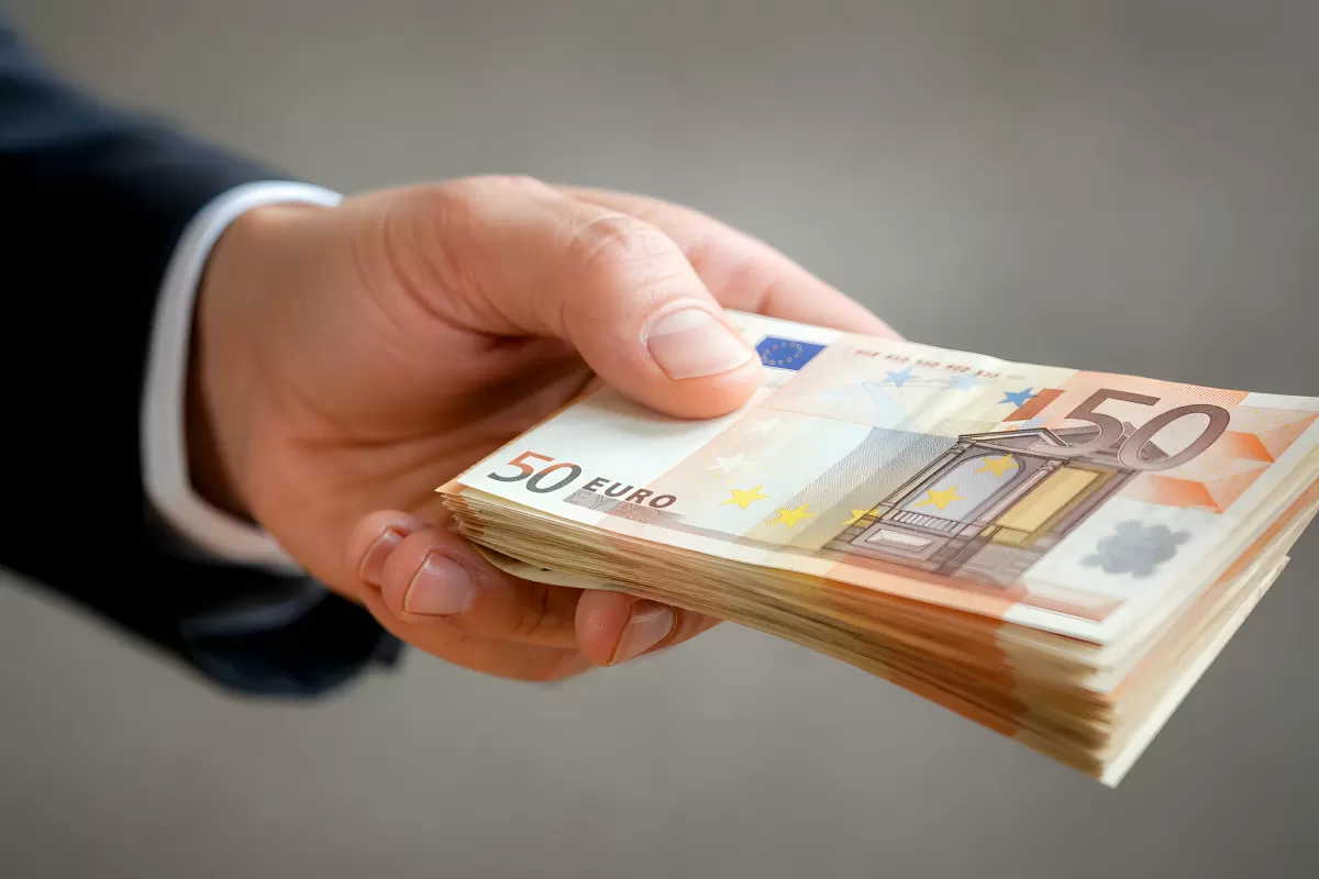 Hand im Anzug reicht einen Stapel 50-Euro-Scheine