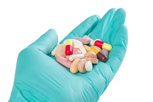Hand in a disposable glove with multicolored pills