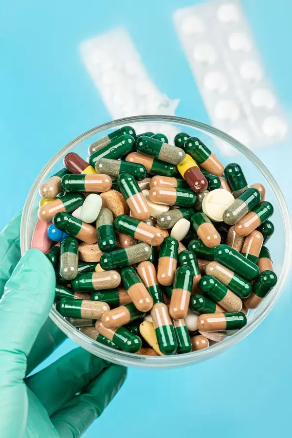 Hand in a glove holds a bowl of medicines