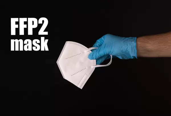 Hand in blue gloves holding FFP2 mask