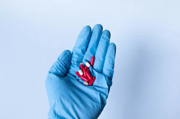 Hand in blue medical gloves holding pills