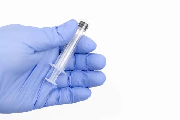 Hand in blue Medical Gloves holds plastic medical injection