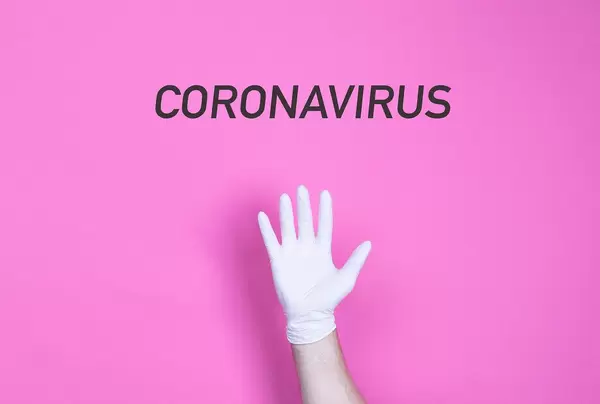 Hand in medical glove with Coronavirus text