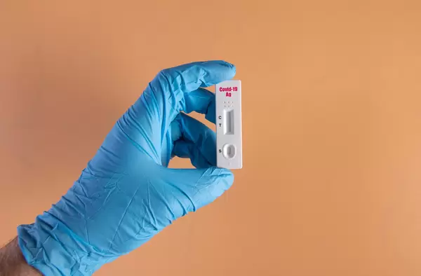 Hand in protective gloves holding rapid antigen test for Covid-19