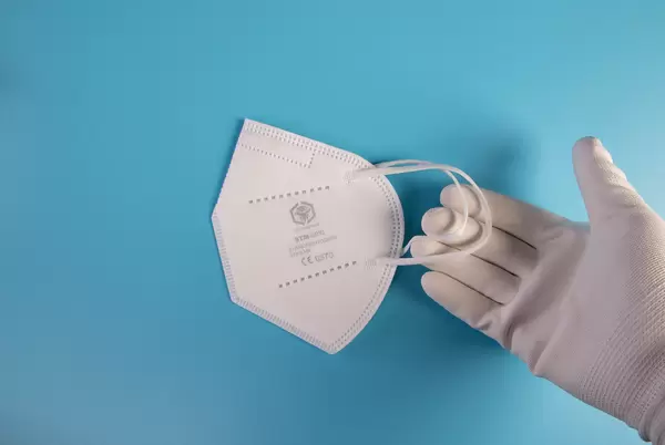 Hand in white gloves holding FFP2 medical face mask