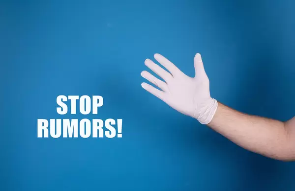Hand in white protective gloves with Stop rumors text