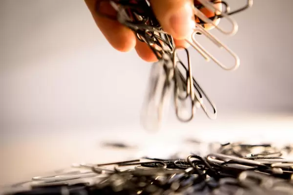 Hand lässt einen Haufen Büroklammern fallen