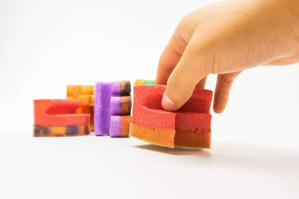 Hand lifting up a house shaped sponge