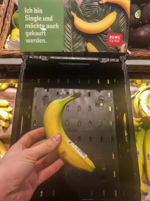 Hand of a customer buying a banana sold individually at a supermarket