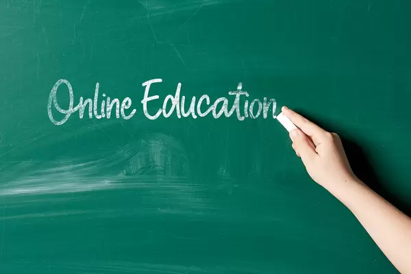Hand of a woman writing on the chalkboard - online education