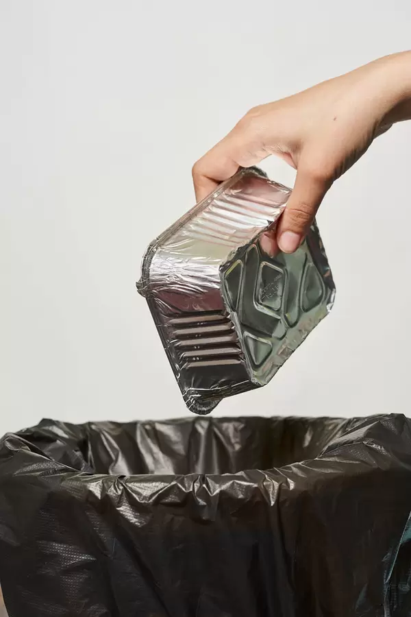 Hand of female throwing used lunchbox into trash bin