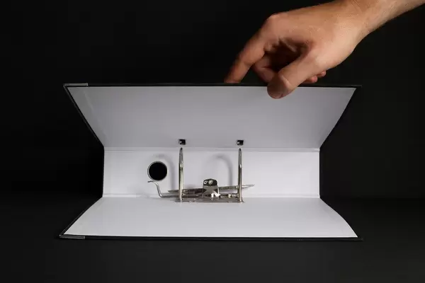 Hand opening empty folder on black background