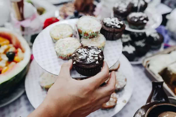 Hand picking up a chocolate cupcake. Table background