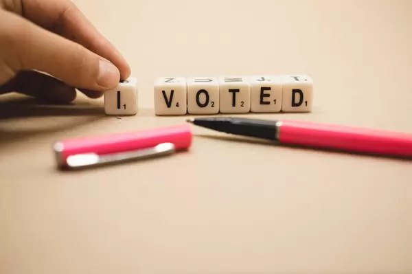 Hand placing dice reading I VOTED