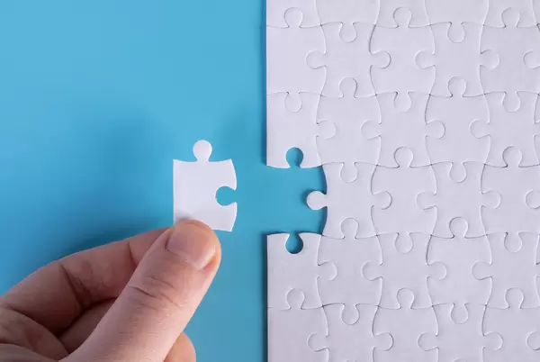 Hand placing the last jigsaw puzzle piece