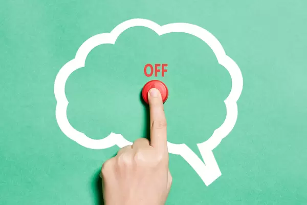 Hand pushing off button in the brain shape. A symbol of turning off the brain or switching off thinking