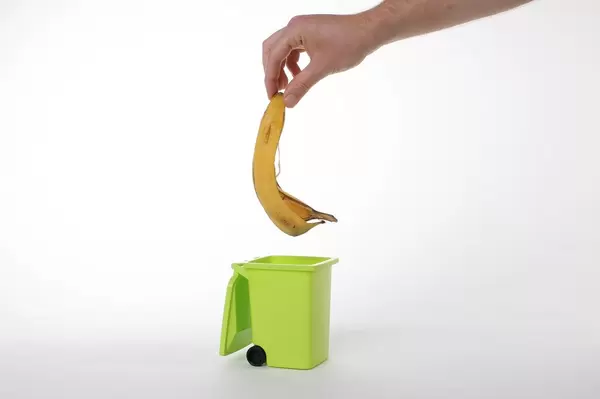 Hand putting banana peel in recycling bio bin