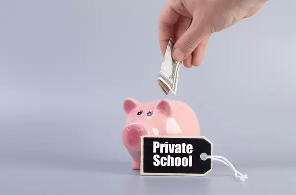 Hand putting money in a piggybank and Private School text