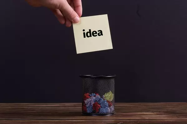 Hand putting paper with Idea text into a trash can