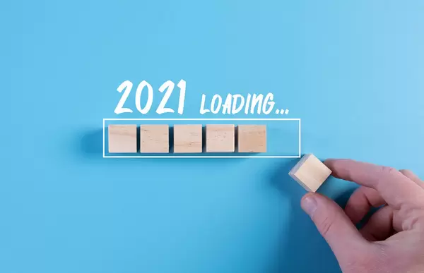Hand putting wooden cube in progress bar with 2021 loading text